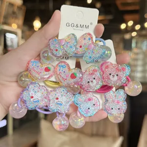 Vista dettagliata di elastici per capelli glitterati per bambini con simpatici ciondoli in resina.