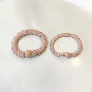 Close-up detail of soft pleated hair scrunchies with round bead, elegant pink hair bands.
