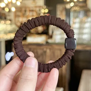 Primer plano de un coletero plisado marrón con abalorio cuadrado elegante, suave y elástico.