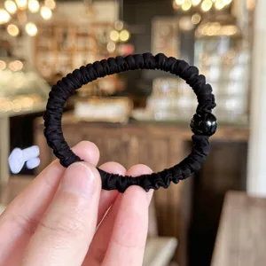Black scrunchie with glossy bead, soft elastic hair tie for daily styling and elegant looks.