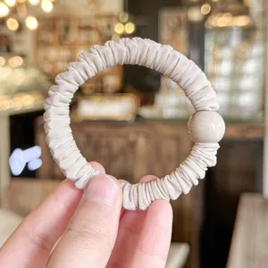 Minimalist pleated hair scrunchie with a glossy bead accent, soft and elastic for women.