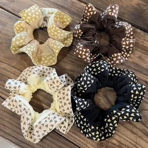 Detalle de coletero con volantes y estampado de corazones, accesorio de pelo de tela suave.