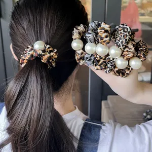 Λεπτομέρεια scrunchie με μοτίβο λεοπάρ και μεγάλη πέρλα, στιλάτο αξεσουάρ μαλλιών.