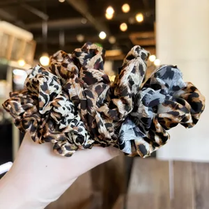Detailed close-up shot of a stylish leopard print hair scrunchie, soft fabric elastic band.