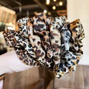 Detailed view of the oversized leopard print hair scrunchie, showing silky smooth fabric texture.