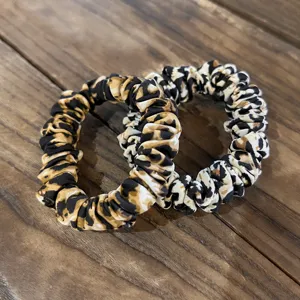 Close-up detail of stylish leopard print hair scrunchies, soft fabric hair ties for daily wear.
