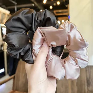 Detailed view of soft satin hair scrunchies in dark brown and pink, perfect ponytail holders.