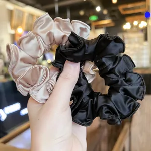 Detailgezicht van elegante satijnen haarrekkers in champagne en zwart, zachte textuur voor haar.