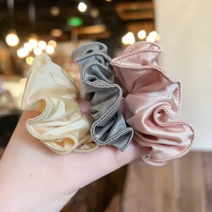 Set van glanzende satijnen haarrekkers in champagne, grijs en roze, zachte haarelastiekjes.