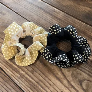 Primer plano detallado de lindos coleteros de tela con estampado de corazones beige y negros.