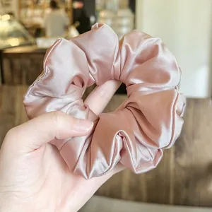 Pink satin padded hair scrunchie detail view, soft shiny fabric ponytail holder close up