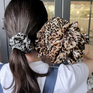Leopard print hair scrunchie detail shot, elegant silk fabric oversized hair accessory for women styling.