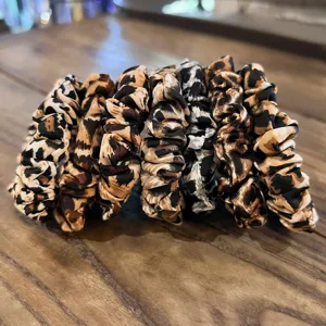 Close-up detail of stylish leopard print hair scrunchies arranged neatly on a wooden table.
