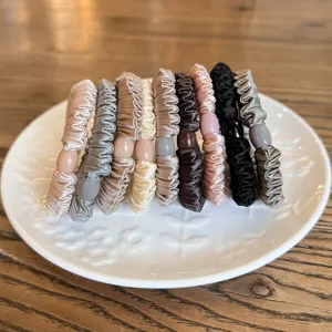 Detailed shot of colorful satin scrunchies with bead accents arranged neatly on a plate.