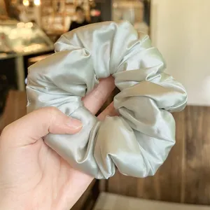 Close-up detail of smooth satin hair scrunchie, soft padded texture for daily gentle hair styling.
