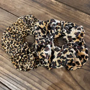 Close-up detail shot of stylish leopard print fabric scrunchies showing soft texture hair tie.
