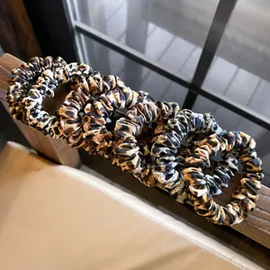 Leopard print hair scrunchies detail view, showing soft fabric texture and elastic band.