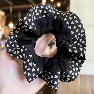 Coletero para el pelo negro y blanco con estampado de corazones y borde con volantes.