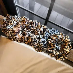 Leopard print scrunchie detail shot, soft fabric hair tie elastic fashion accessory.