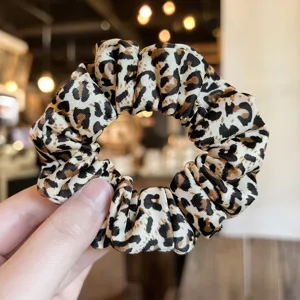 Leopard print hair scrunchie detail view, soft fabric elastic hair band accessory.