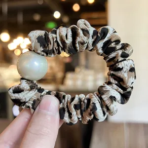 Scrunchie μαλλιών με λεοπάρ μοτίβο και λεπτομέρεια πέρλας, αξεσουάρ μόδας κοντινό.