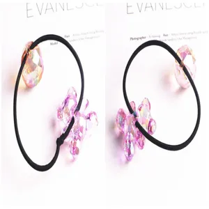 Gros plan des détails d'élastiques à cheveux avec pendentifs ours et boule en cristal irisé.
