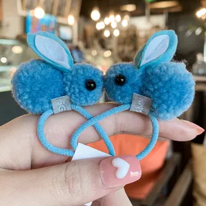 Close-up detail of cute blue plush bunny hair ties with soft fluffy pom-poms and sweet ears.