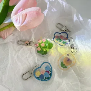 Detailed view of cute acrylic tulip keychains on white crinkled paper background, chic design.