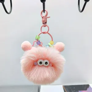 Detaillierte Nahaufnahme eines süßen rosa flauschigen Monster-Schlüsselanhängers mit Kulleraugen.