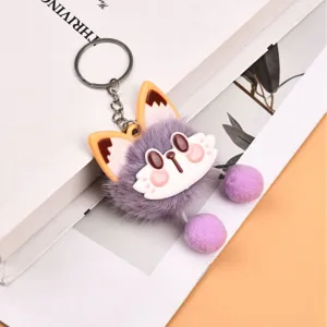 Plush fox keychain detail shot, featuring soft purple fur, cute cartoon face and dangling pom poms.