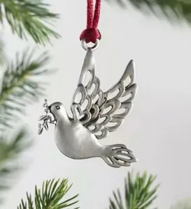 Detailed shot of a silver metal peace dove Christmas ornament with red ribbon hanging.