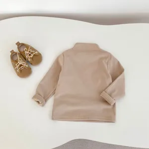 Vista dettagliata del top dolcevita beige per bambini piccoli con scarpe abbinate.