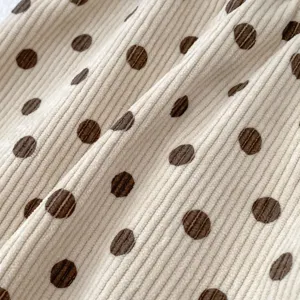 Primo piano del dettaglio in tessuto a coste con pois marroni su sfondo beige per abbigliamento.