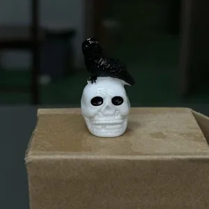 Detailed view of Halloween resin crow on skull figurine, miniature decor ornament for party.