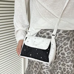 Small crossbody bag with star pattern, black and white layered flap design, chic fashion accessory.