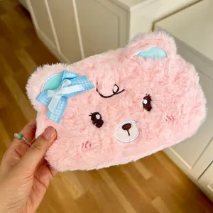 Cute pink plush bear pencil case with blue bow, soft fluffy stationery storage pouch for students.