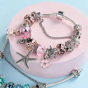 Silver snake chain charm bracelet with pink floral beads and starfish charms for women.