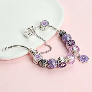 Close-up detail of silver alloy charm bracelet featuring purple cherry blossom beads and crystals.