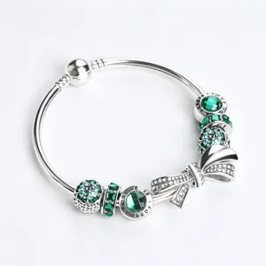 Silver charm bracelet with sparkling green crystals and elegant bow design for women fashion.