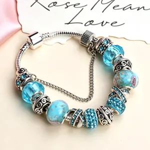 Primo piano del bracciale charm vintage con perle di vetro blu e dettagli decorativi in argento.