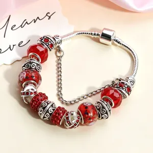 Primo piano dettagliato di bracciale charm in argento con perle di vetro rosse e cristalli.
