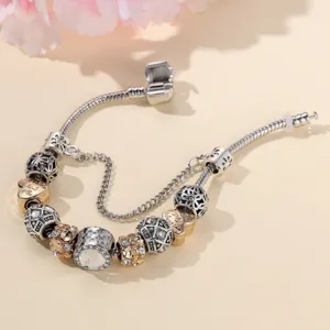 Zilverkleurige goudkleurige DIY bedelarmband met kristalparels en hartvormige hangers.