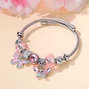 Gedetailleerde close-up van roestvrijstalen uitrekbare armband met roze kralen en vlinderbedels.