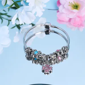 Silberfarbenes Bettelarmband mit bunten Kristallperlen und rosa Kleeblatt-Anhänger.