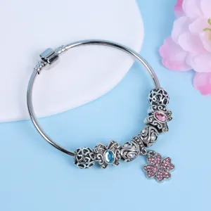 Nahaufnahme des silbernen Bettelarmbands mit filigranen Perlen und funkelndem Kleeblatt-Anhänger.