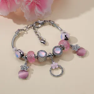 Dettaglio del braccialetto di perle in occhio di gatto rosa con ciondoli di fiori di strass.