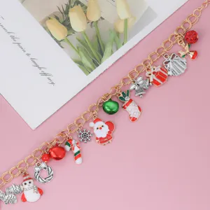 Gros plan d'un charmant bracelet doré de Noël orné de divers pendentifs festifs colorés.