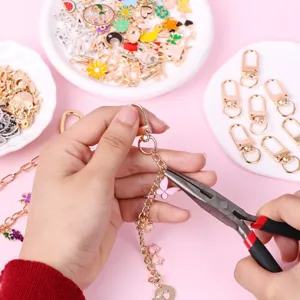 Detail view of DIY keychain making kit showing hands assembling charms and chains with pliers.