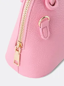 Pink dome handbag detail shot, classic shell crossbody bag with gold hardware and zipper.