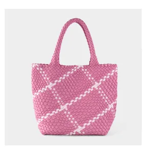 Pink and white woven tote bag detail showing intricate intrecciato pattern and double handles.